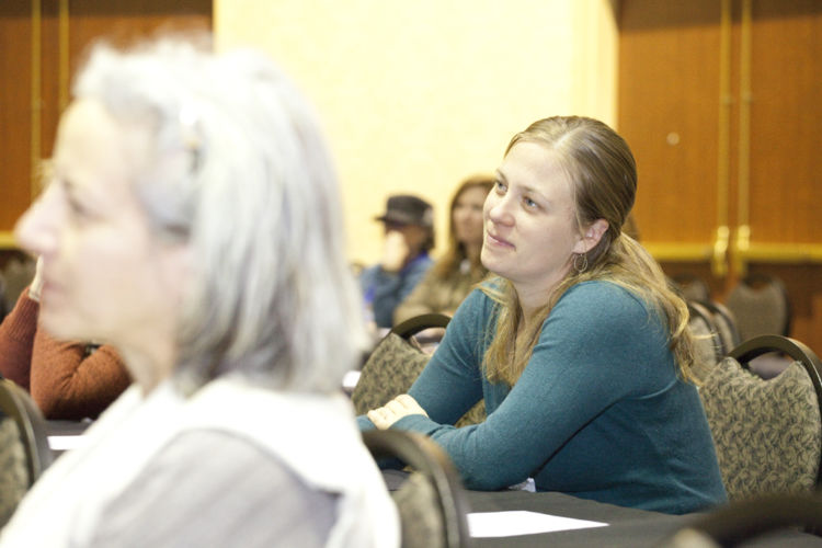 A conference attendee listens happily to a presentation.