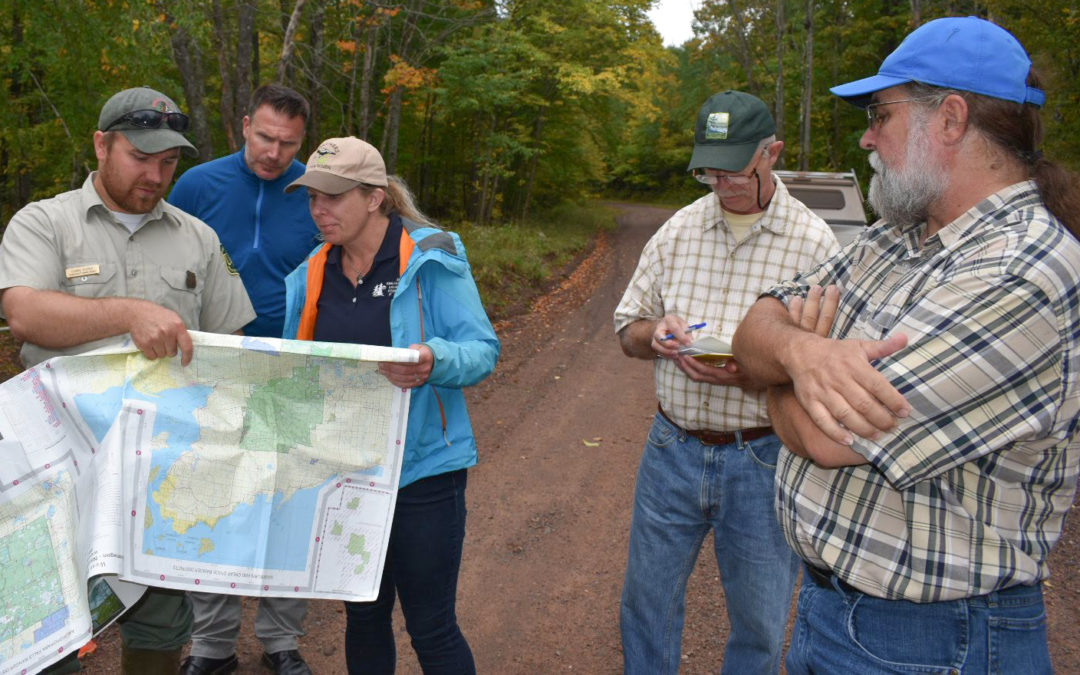People gathered around a map in a natural area, with WWA's Tracy Hames in the foreground.