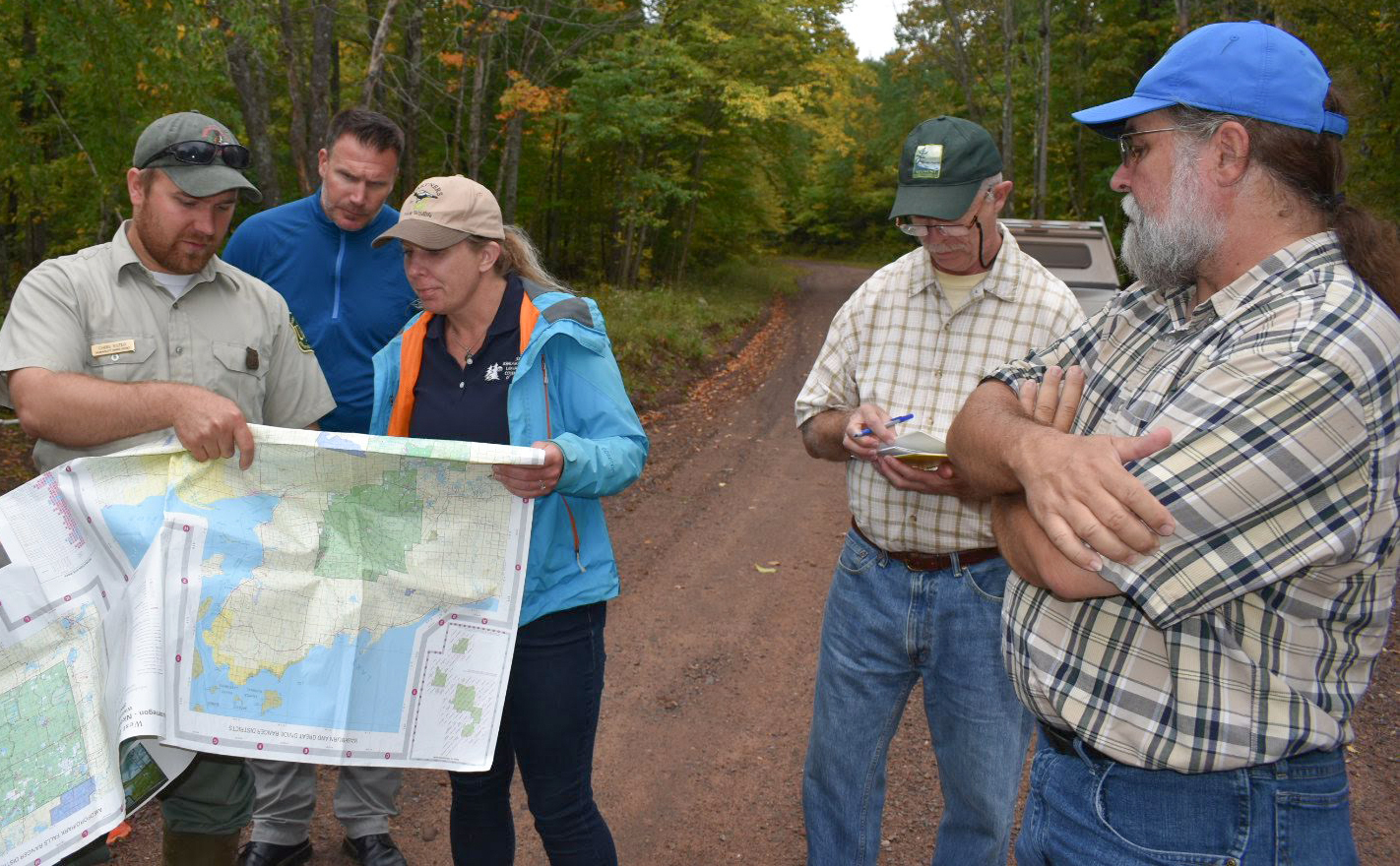 People gathered around a map in a natural area, with WWA's Tracy Hames in the foreground.