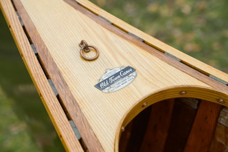 The white ash bow deck of a canoe with showing an Old Town Canoe company decal.