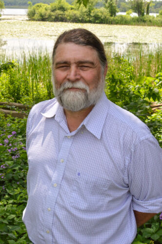 Photo of Tracy Hames standing in front of a wetland.